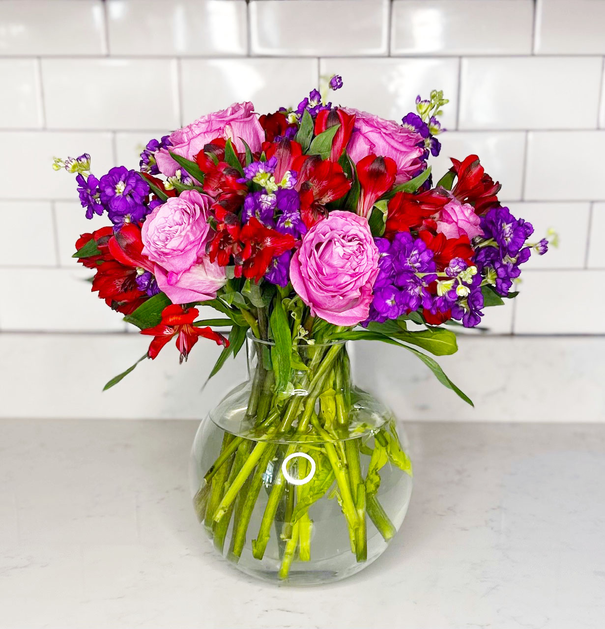 Dark pink Garden Roses, Red Alstroemeria and Purple Stock flowers arrangement in Balloon Vase