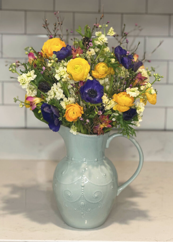 White stock flowers, purple Wax Flowers, blue anemone flowers, yellow Ranunculus flowers, Pink & Yellow Freesia, light blue vase, blue pitcher vase, Lenox French Perle vase, floral arranging, floral accessories